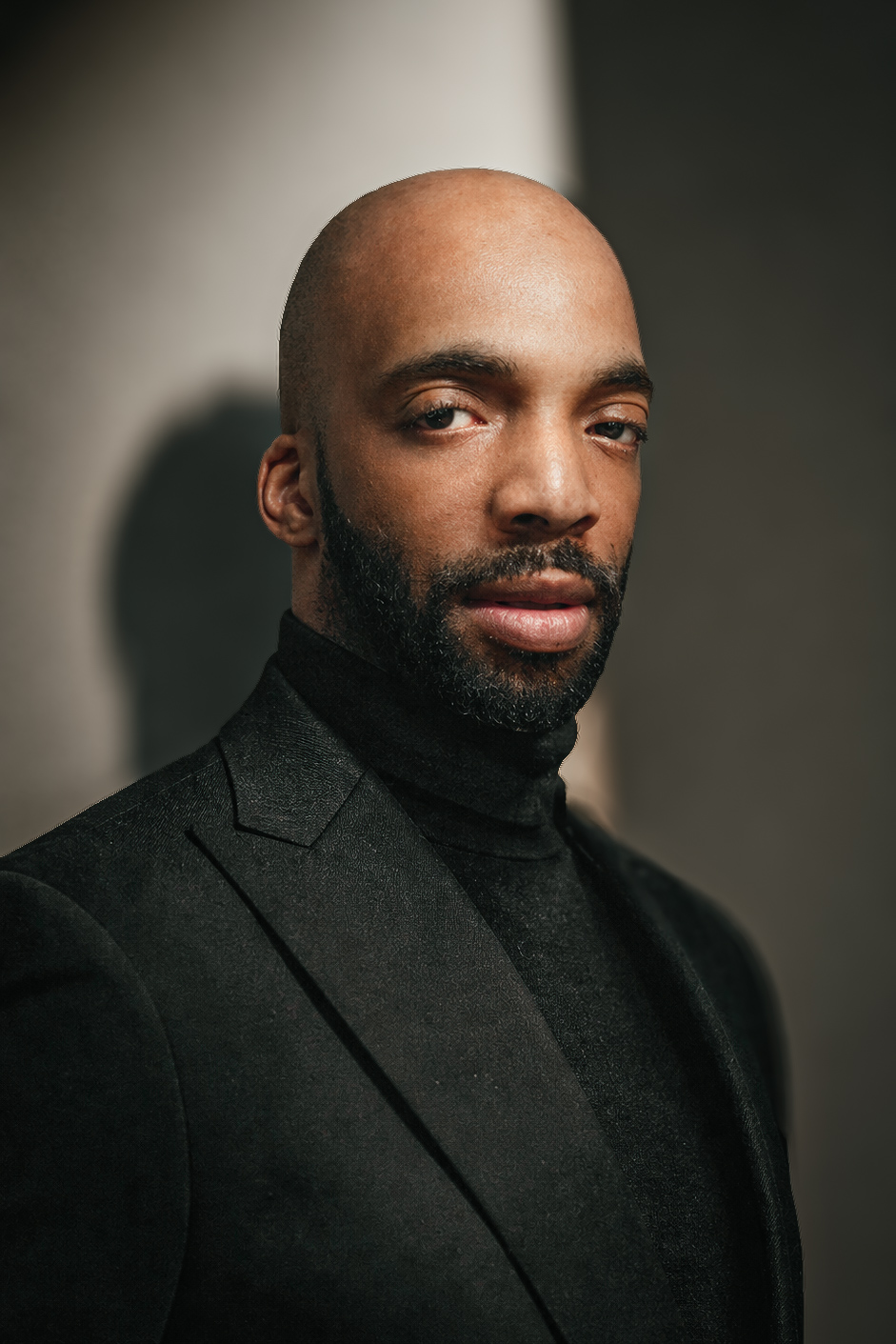 Portrait of Brandon Thomas wearing a black turtleneck and tailored black jacket