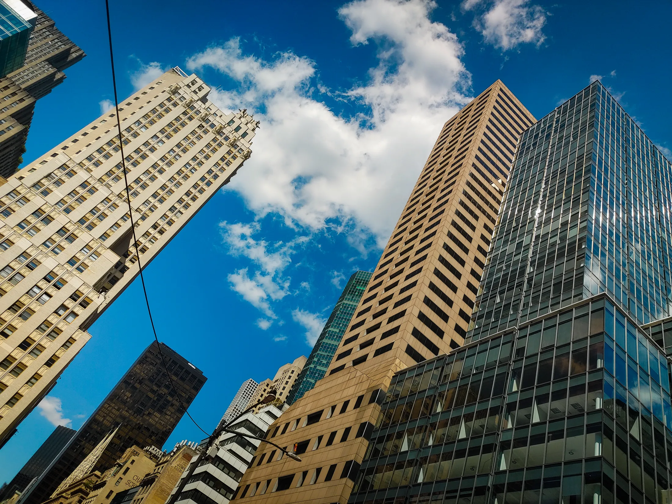 Low-angle view of Manhattan skyscrapers framing a vivid blue sky