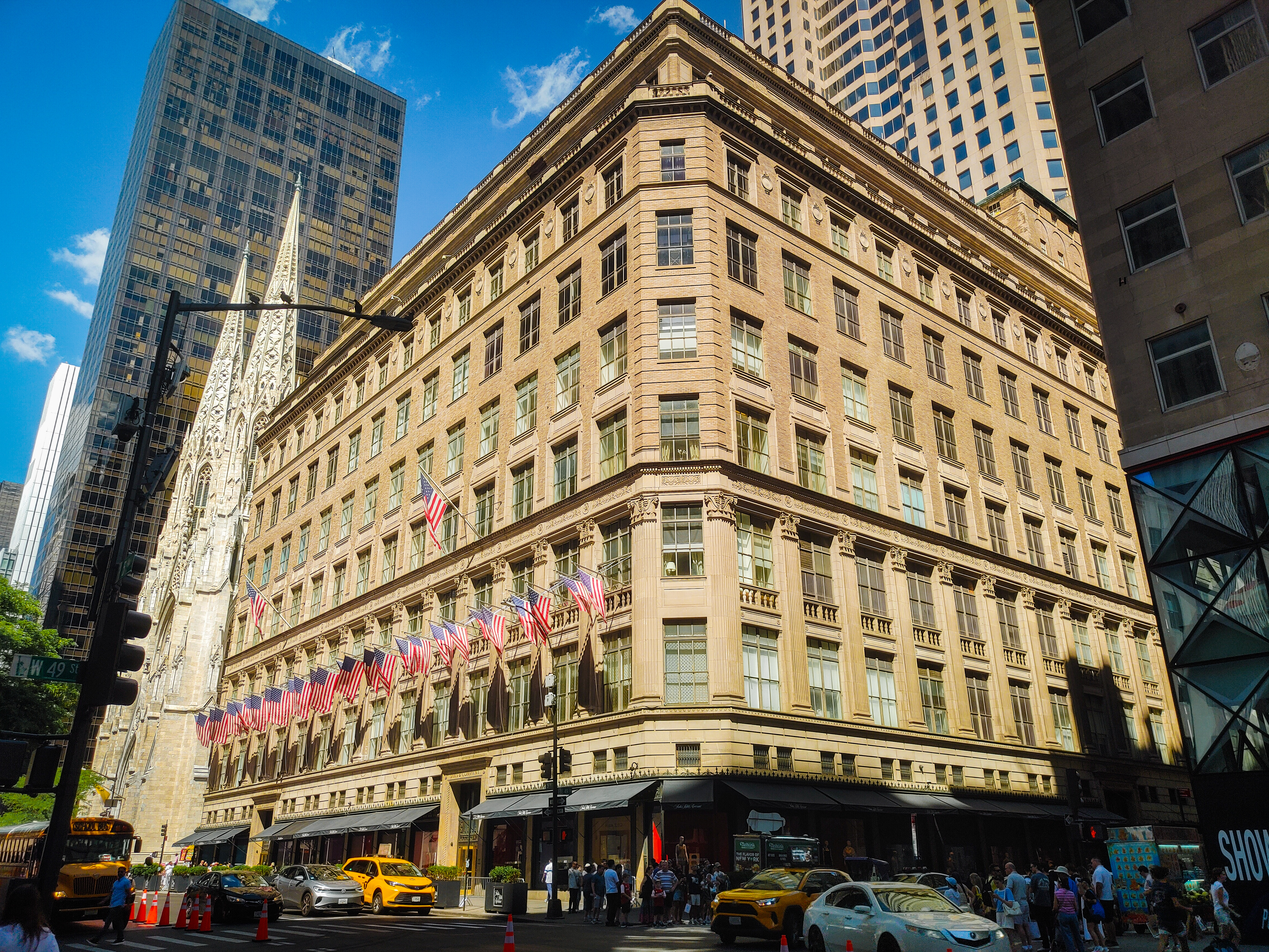 Sunlit Fifth Avenue architecture with flags, yellow taxis, and St. Patrick's Cathedral
