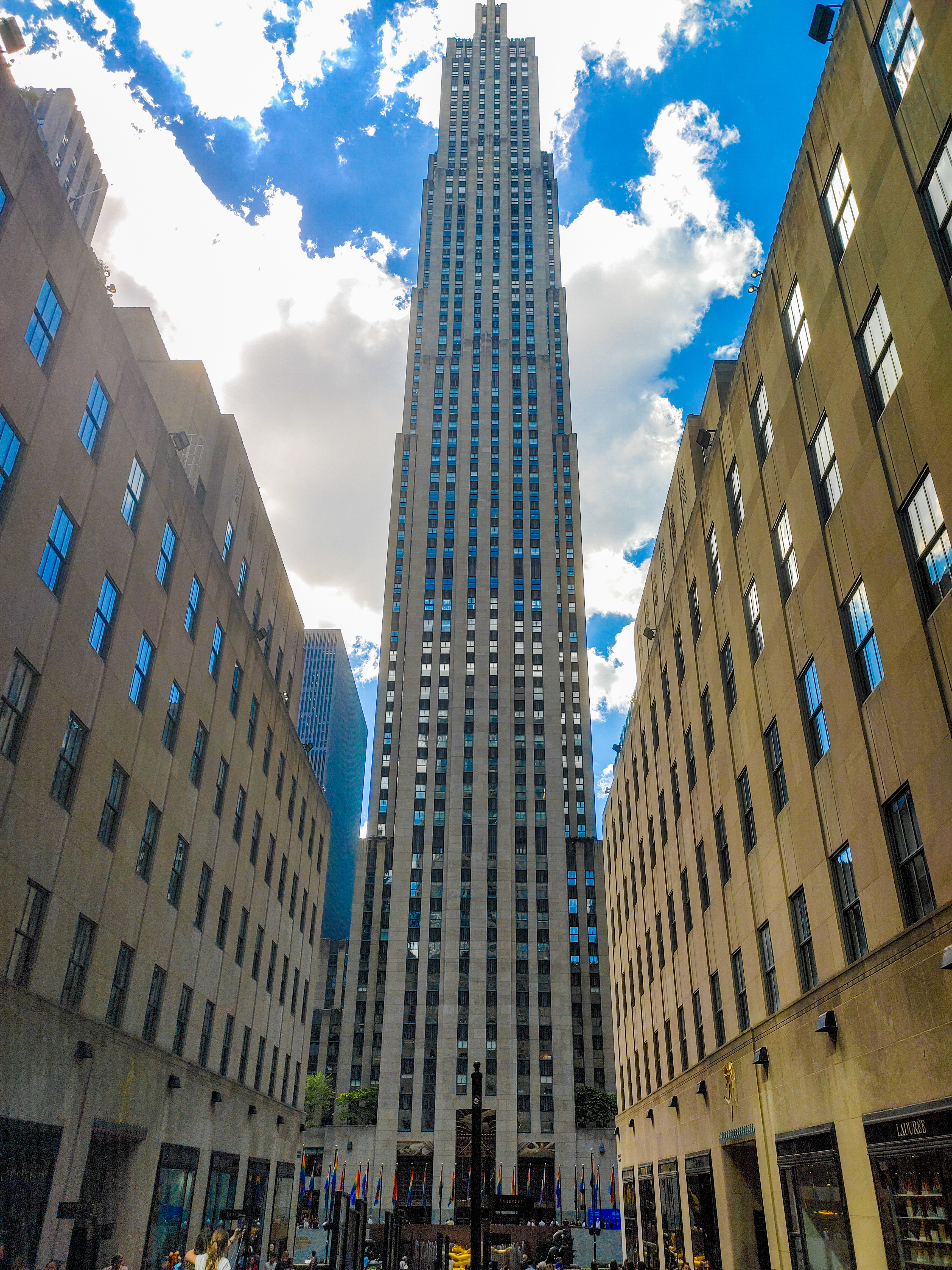 30 Rockefeller Plaza rising symmetrically between stone buildings into a blue sky