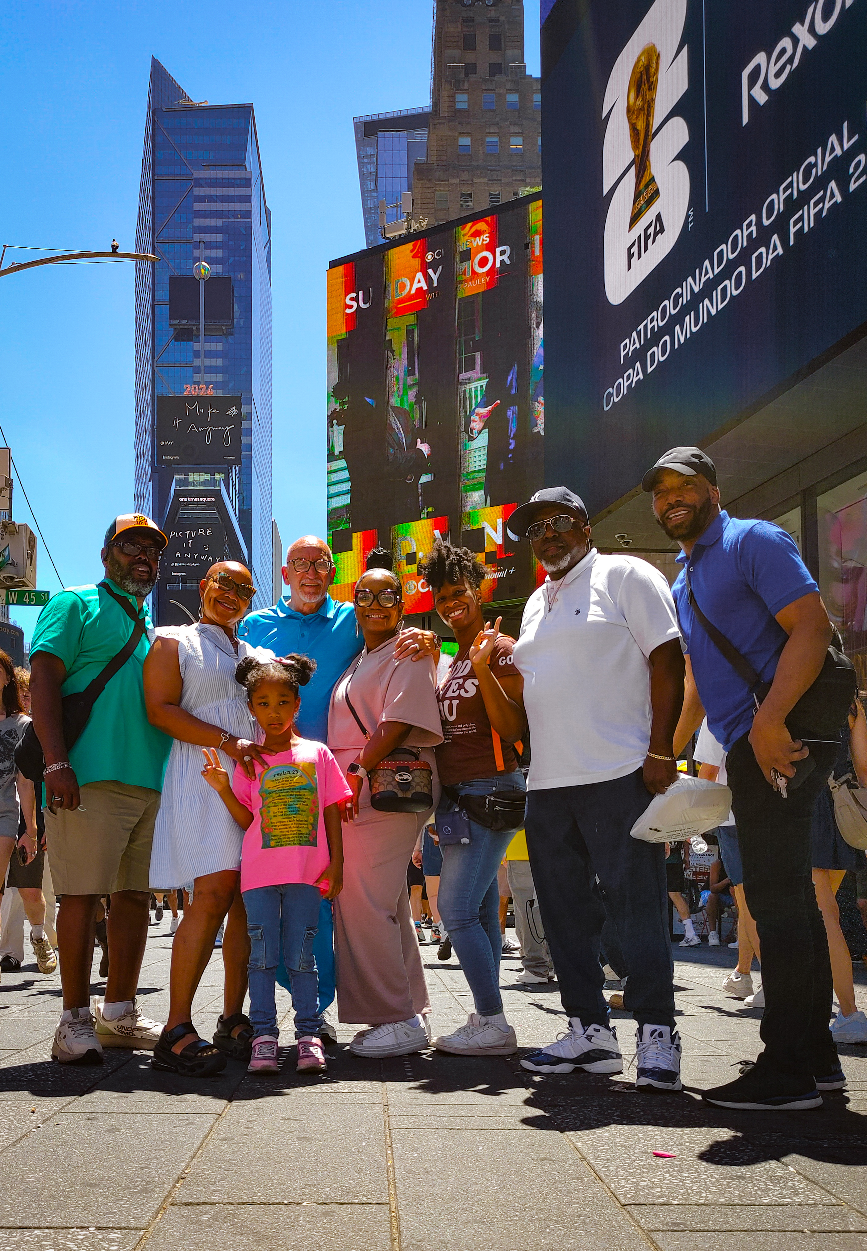 A multigenerational group posing together in sunny Times Square